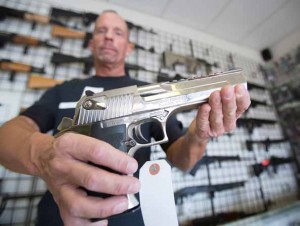 John Byrne/Tribune Kevin Marriott of Juggernaut Arms, a Sparks gun shop, displays a semi-automatic handgun in the store’s newly expanded showroom. 